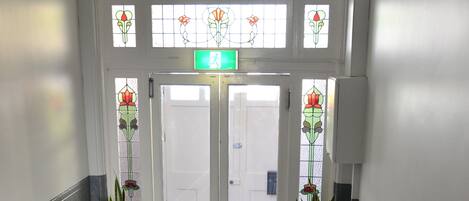 A staircase with a green carpet, white balusters, and a door with stained glass windows.