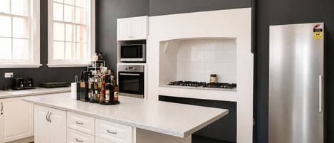 Una cocina moderna con gabinetes blancos, un refrigerador de acero inoxidable y una estufa a gas.