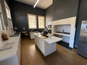A modern kitchen with white cabinetry, a central island, a microwave, and a stove. - Shoreline Lodge Geraldton (Geraldton)