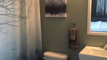 Een bad/douchecombinatie, een haardroger, handdoeken, zeep