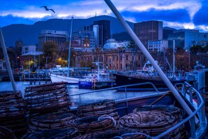 A harbor with boats docked, a cityscape in the background, and a mountain. - Luxury Hobart Waterfront Apartment (Hobart)