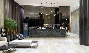 A modern reception area with a marble counter, black chairs, and a large potted plant. - Hotel Ohevday (Namwon)