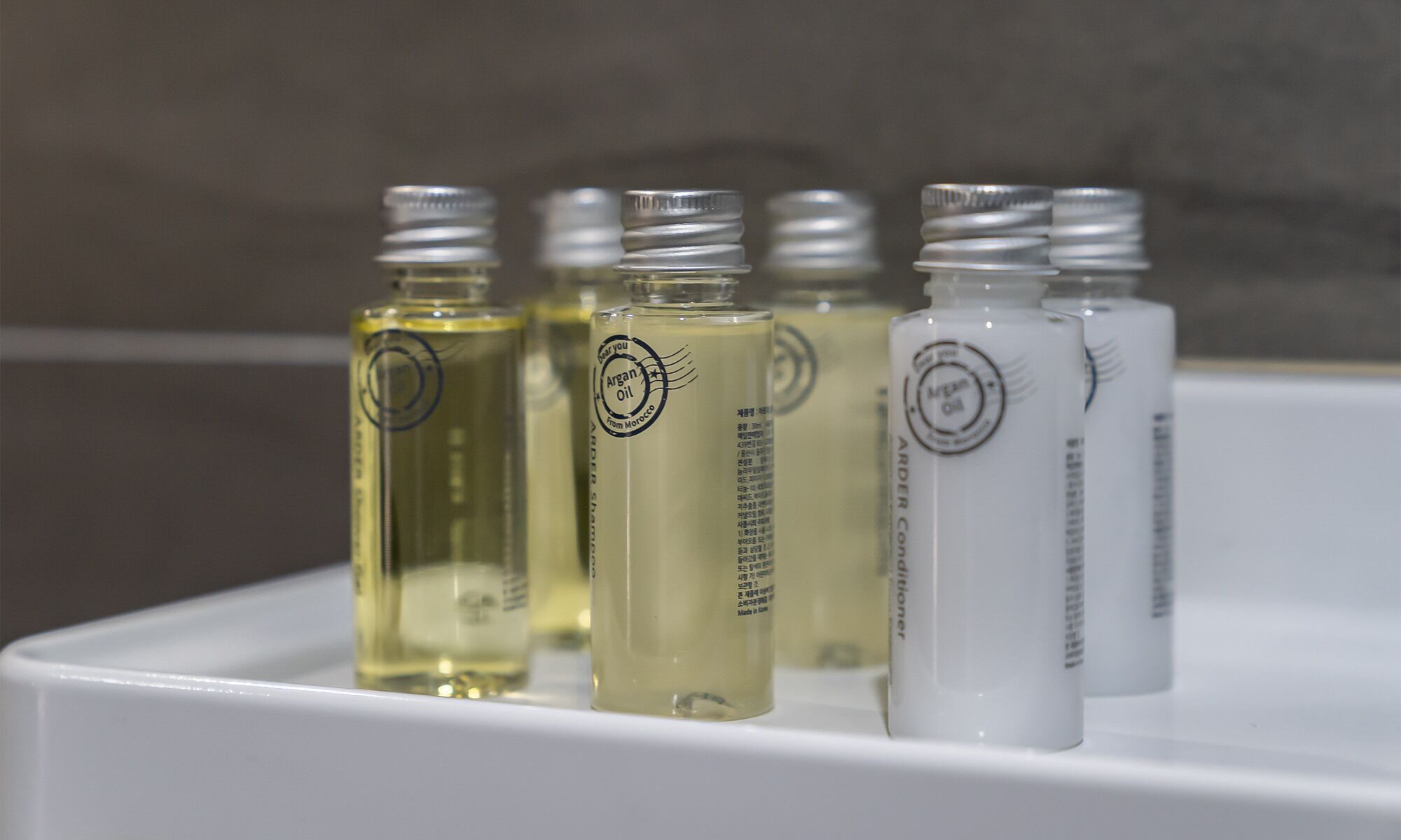Una hilera de botellas con etiquetas sobre un estante blanco.