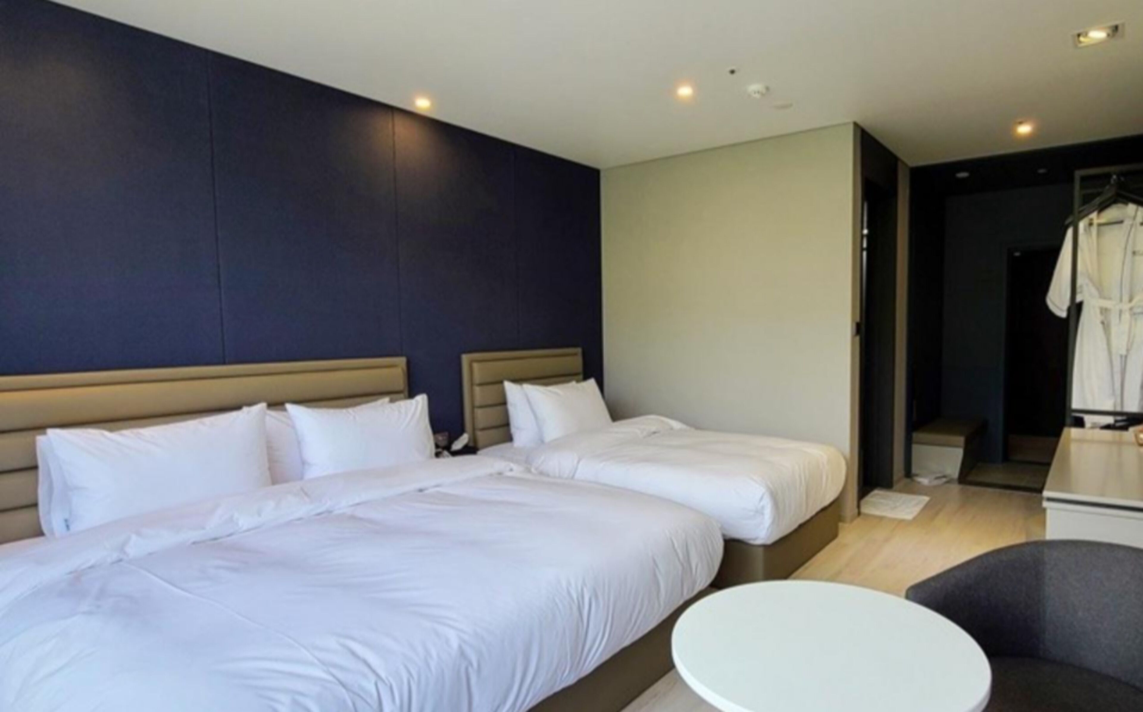 Habitació d'hotel amb dos llits, una taula rodona i un penjador de robes.