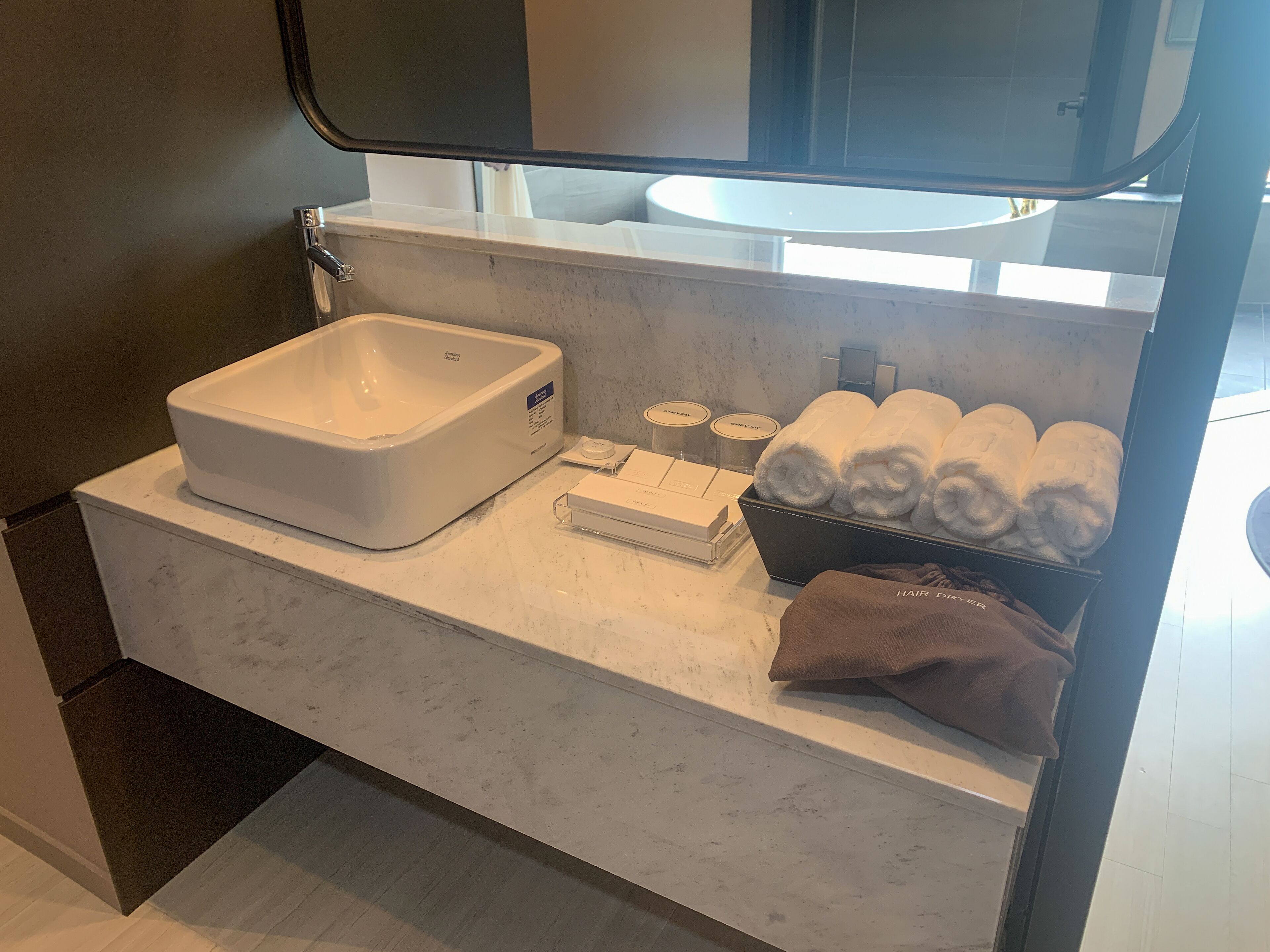 A bathroom with a white sink, a large mirror, and a towel rack.
