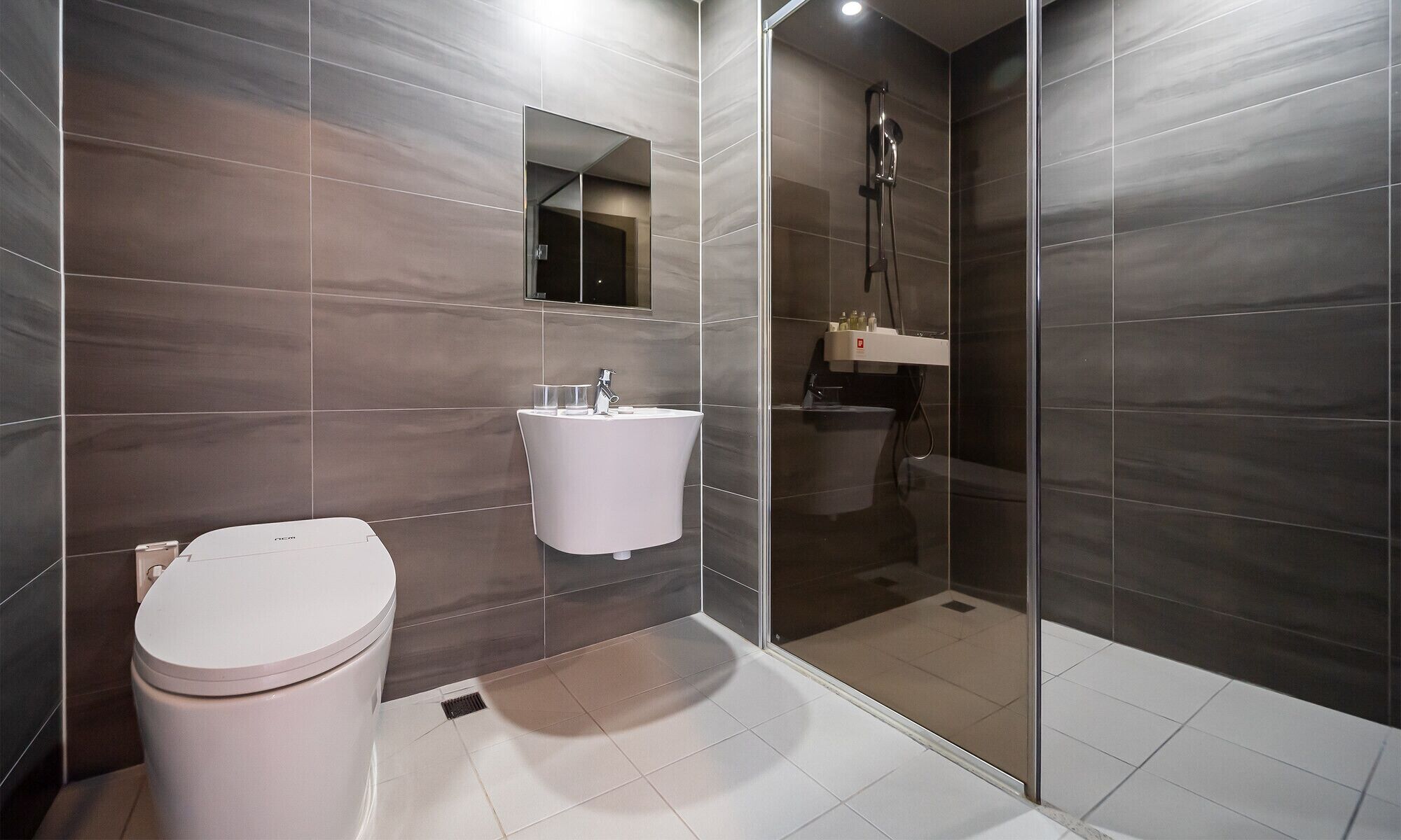 A modern bathroom with a toilet, sink, and shower.