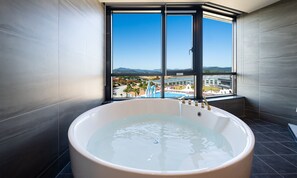 A modern bathroom with a large bathtub, a view of a resort, and a large window. - Hotel Ohevday (Namwon)