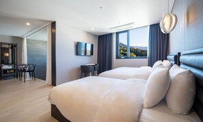 A modern hotel room with two beds, a desk, a chair, a TV, and a large window with a mountain view. - Hotel Ohevday (Namwon)