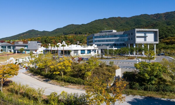A modern hotel with a central courtyard, surrounded by lush greenery and a mountainous backdrop. - Hotel Ohevday (Namwon)
