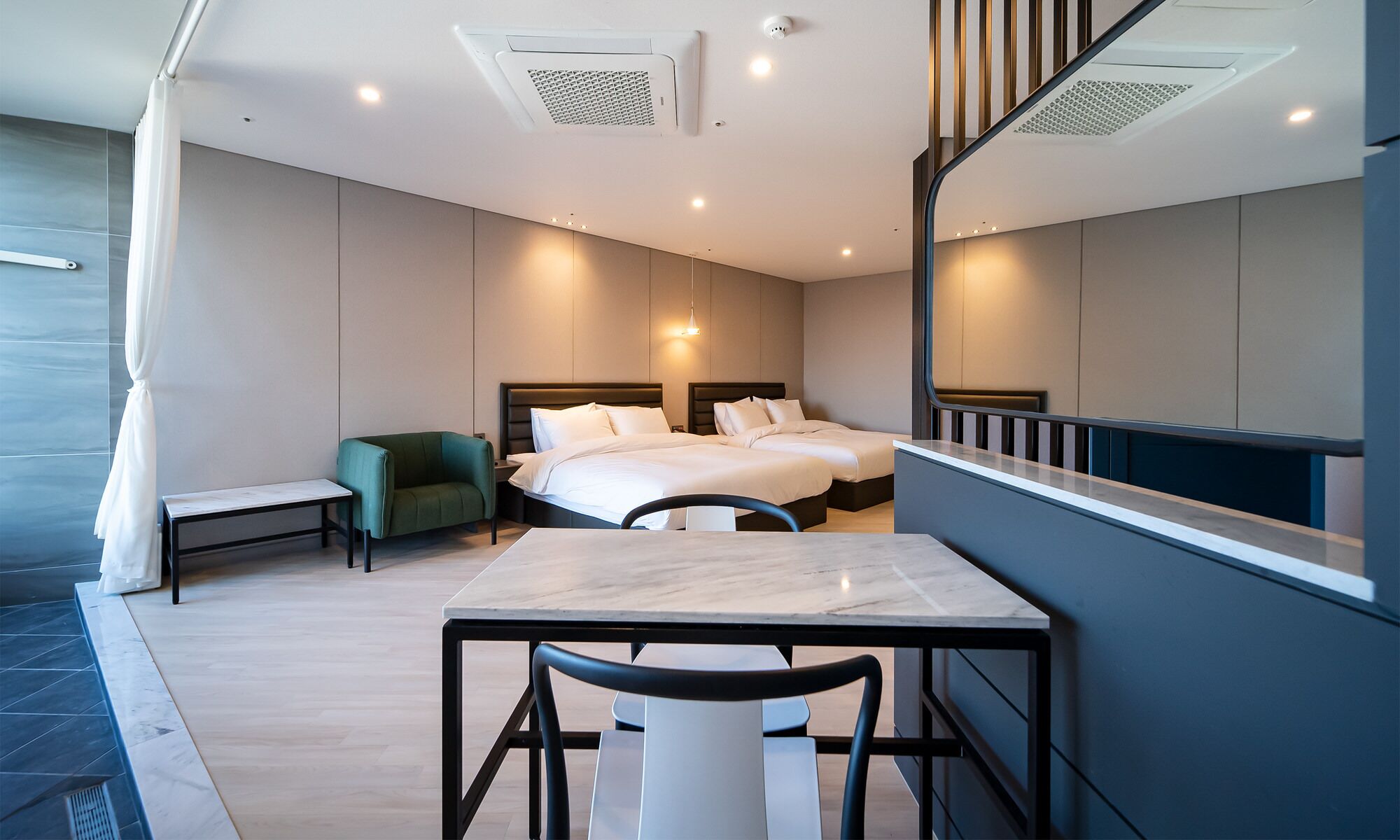 A modern hotel room with a large bed, a desk, a chair, and a small table.