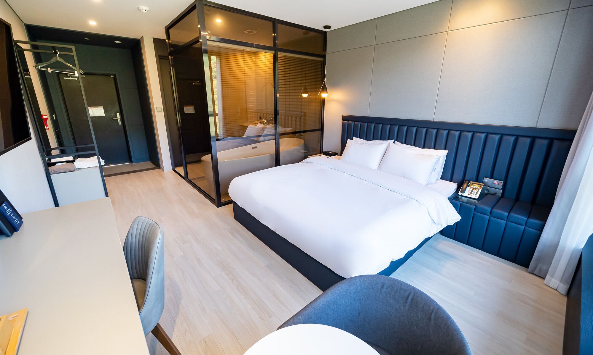 Una habitación de hotel moderna con una cama grande, un escritorio y una zona de estar.