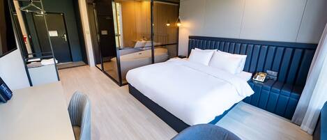 Una habitación de hotel moderna con una cama grande, un escritorio y una zona de estar.