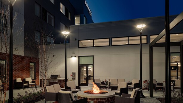 An outdoor patio with a fire pit, seating, and a building in the background. - Residence Inn by Marriott Columbus Airport (Columbus)