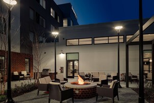 Un patio al aire libre con una chimenea, asientos y un edificio al fondo.