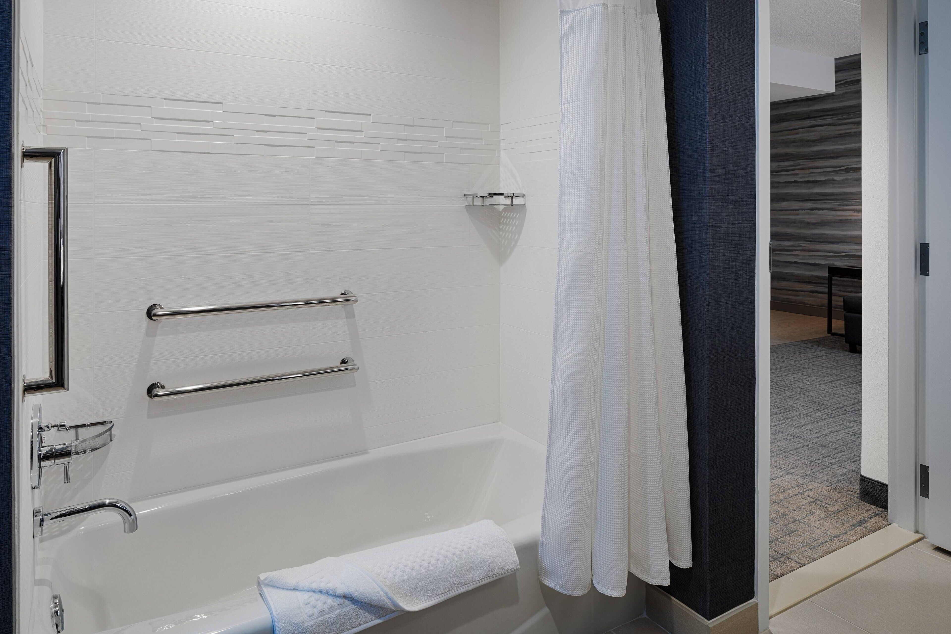 Une salle de bain moderne avec une baignoire, un rideau de douche et un porte-serviettes.