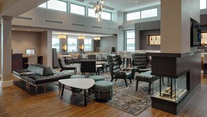 A spacious hotel lobby with a modern design, featuring a fireplace, comfortable seating areas, and large windows providing natural light. - Residence Inn by Marriott Columbus Airport (Columbus)
