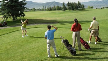 A golf course with a clear view of the green, fairways, and distant mountains.