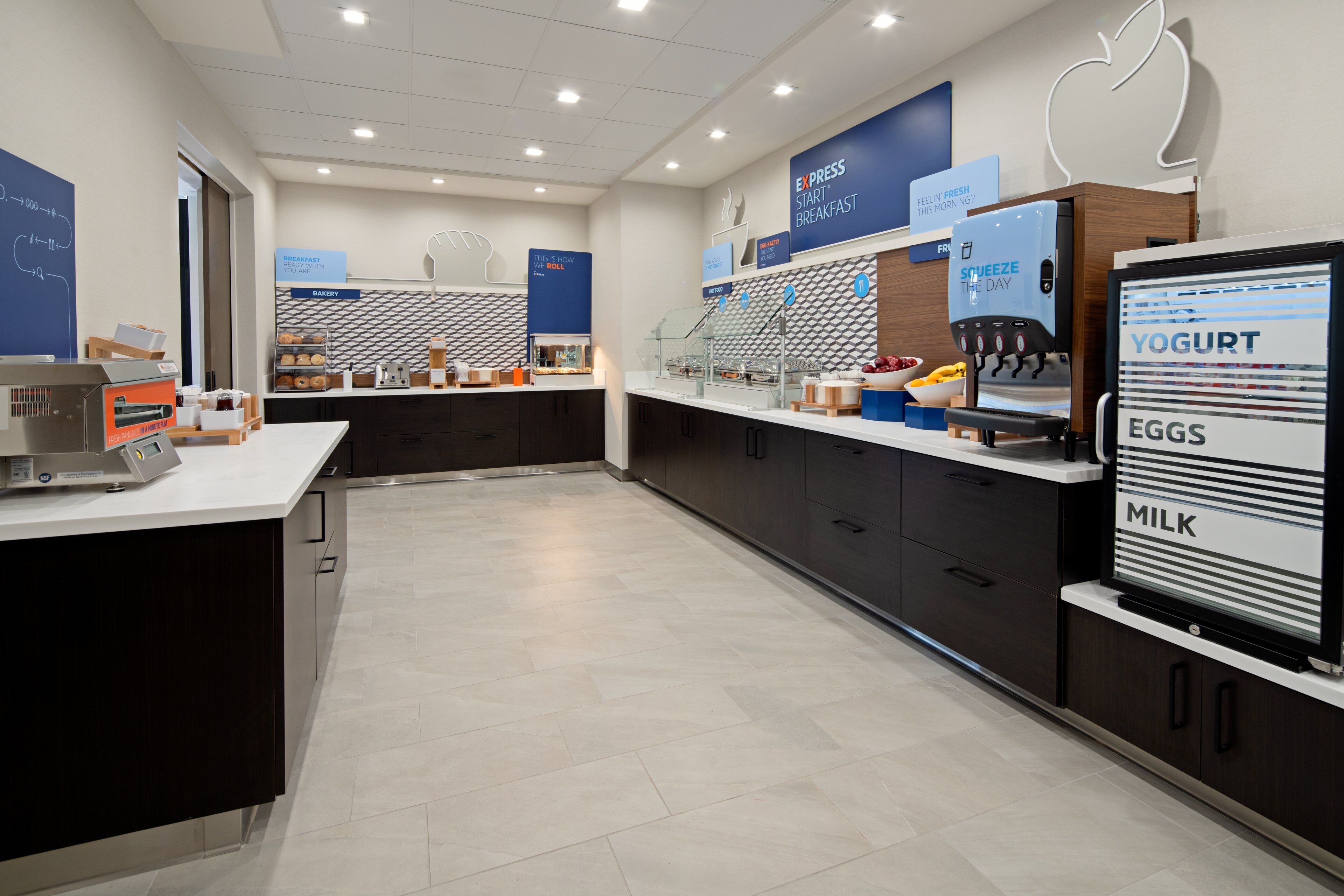 A modern breakfast area with a digital menu display, a coffee machine, and a yogurt dispenser.