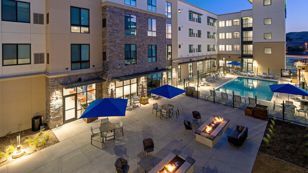 Un patio de hotel con piscina, mobiliario exterior y una chimenea.