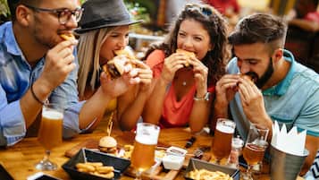 A group of people dining at a restaurant with burgers, fries, and beer.