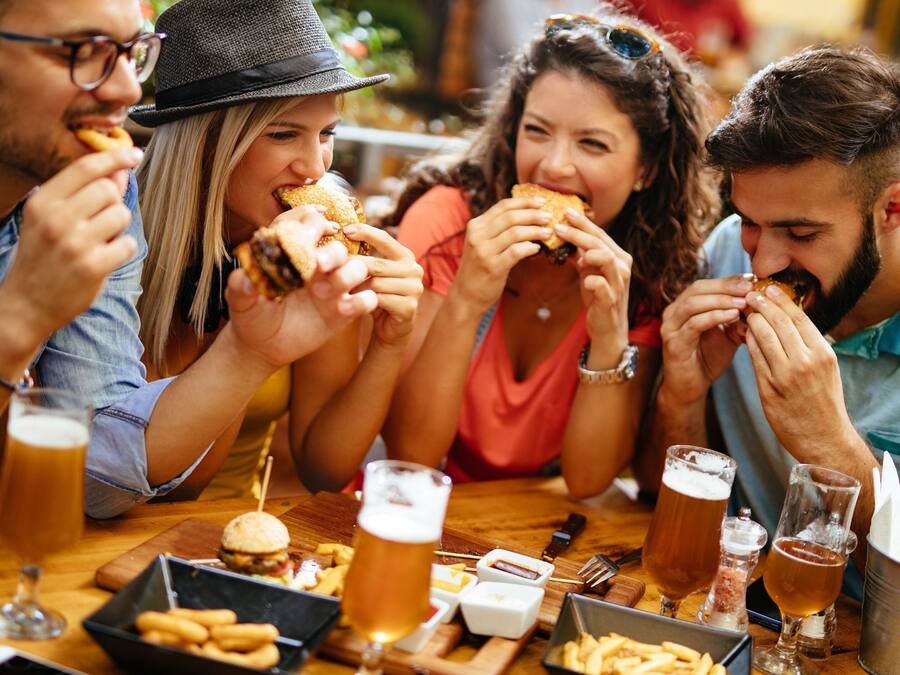 A group of people dining at a restaurant with burgers, fries, and beer.