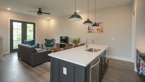 A modern kitchen with a central island, dark cabinetry, and pendant lighting.