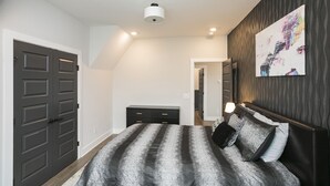 A bedroom with a bed, a dresser, a wall-mounted artwork, and a ceiling light.