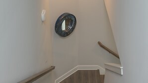 A wooden staircase with white walls and a round mirror on the wall.