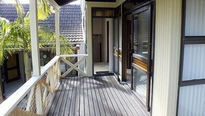A wooden deck with a glass door leading to a room. - Wharepekapeka - Russell Holiday Home (Russell)