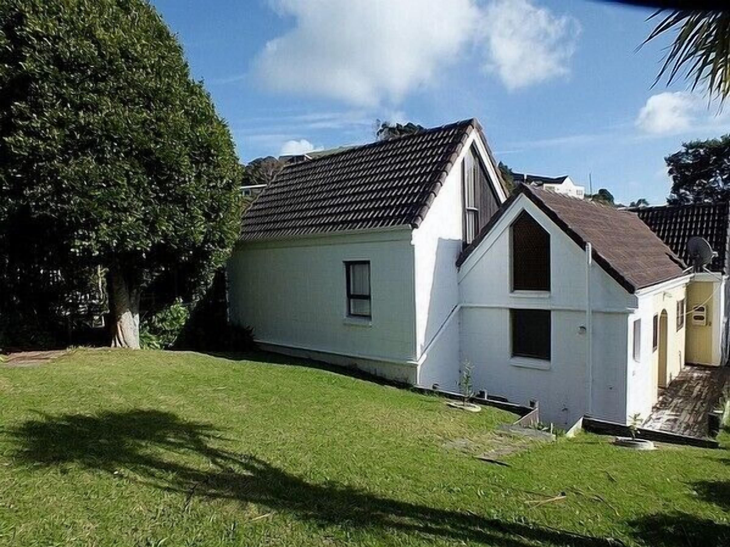 A two-story house with a sloped roof, a small front porch, and a well-maintained lawn.