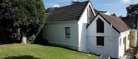 A two-story house with a sloped roof, a small front porch, and a well-maintained lawn.