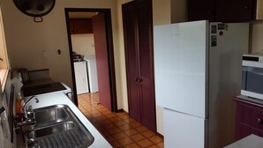 A compact kitchen with a sink, stove, and a refrigerator. - Wharepekapeka - Russell Holiday Home (Russell)