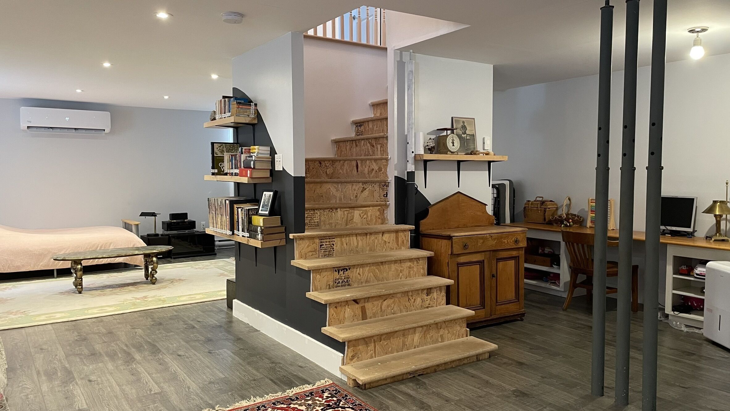 A modern interior with a spiral staircase, a bed, a desk, and a bookshelf.