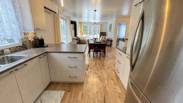 Una cucina moderna con isola centrale, elettrodomestici in acciaio inossidabile e zona pranzo illuminata da un lampadario.