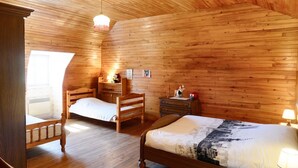 Ein Zimmer mit Holzwänden, zwei Betten, einem Holzstuhl, einem Nachttisch und einem Fenster.