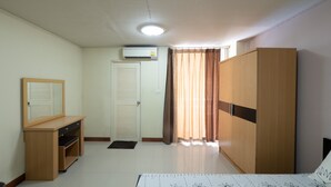 A bedroom with a bed, a wardrobe, a desk, a mirror, a door, and a window with curtains.