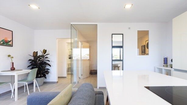 A modern living space with a sofa, a dining table, a kitchen area, and a glass partition. - Cozy "Minimalist Apartment La Pecera" with Wi-Fi (Adeje)