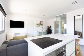 Una cocina moderna con una isla central, horno empotrado y una zona de comedor con sillas y mesa.