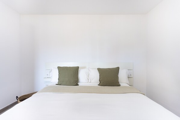 A single bed with a white headboard, two pillows, and a beige blanket.
