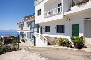 A coastal building with balconies, a staircase, and potted plants.