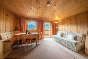 Un intérieur en bois comprenant une table à manger, des chaises, un canapé et une vue sur les montagnes.