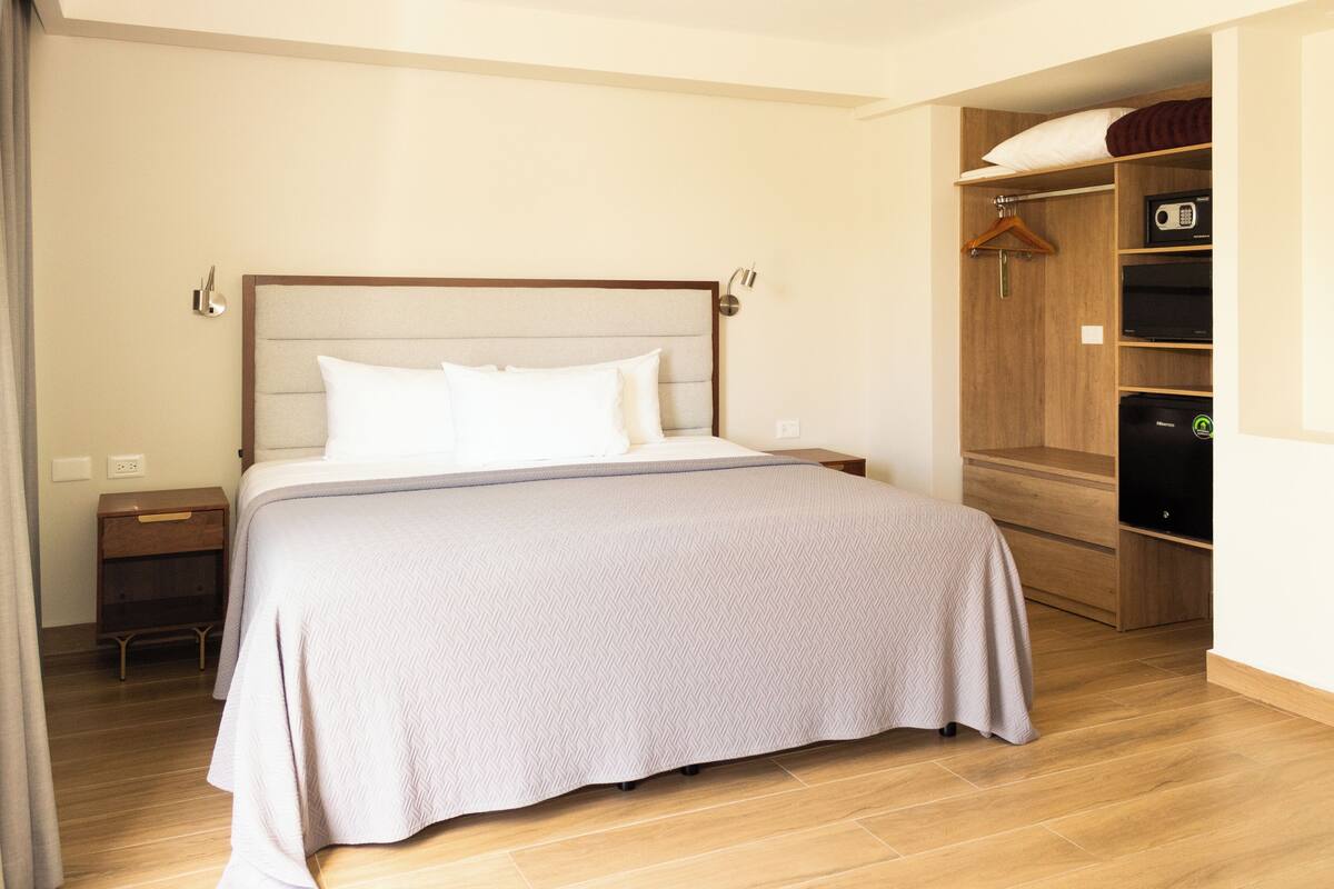 A neatly arranged bedroom with a bed, bedside tables, a wardrobe, and a mirror.
