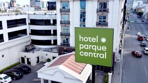 Un hotel con un grande cartello che riporta la scritta 'hotel parque central' e un parcheggio in primo piano.