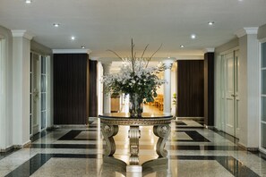 A hallway with a central table featuring a floral arrangement, flanked by doors and a checkered floor. - Hotel Parque Central Monterrey (Monterrey)