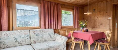 Een houten interieur met een bank en een eettafel.