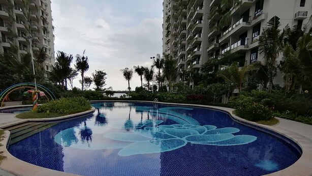 A swimming pool with a floral design, surrounded by palm trees and modern apartment buildings. - Forest City Staview Bay by Wastone (Gelang Patah)