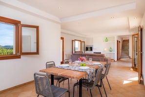A dining area with a table set for two, a sofa, and a view of the outdoors.