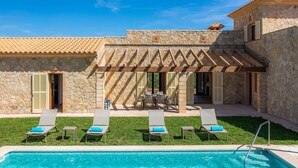 Un bâtiment en pierre doté d’une piscine, d’un espace extérieur aménagé et d’une pergola.