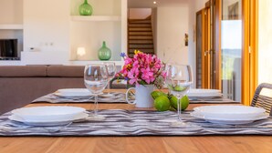 Une table à manger dressée avec des assiettes, des verres et un vase de fleurs.
