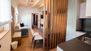 Una cuina compacta amb disseny modern, una zona de menjador amb una banca i un espai d'estar acollidor amb sofà i cadires.